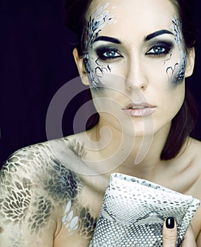 Fashion portrait of pretty young woman with creative make up like a snake, fashion victim with python skin clutch luxury