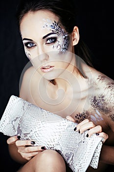 fashion portrait of pretty young woman with creative make up like a snake, fashion victim with python skin clutch luxury