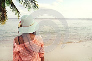 Fashion portrait rear of happy young beautiful woman to wear straw hat - stand on the beach in summer.