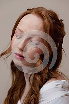 Fashion Portrait of redhead young woman with white extended eyelashes with closed eyes. Concept facial skin care