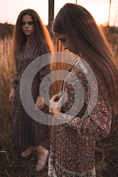 Fashion portrait of two beautiful girls at the sunset field wearing boho styled clothing.