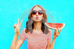 Fashion portrait woman is holding a slice of watermelon and blowing lips