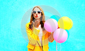 Fashion portrait woman holds balloons sends an air kiss in yellow