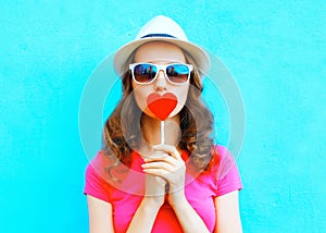 Fashion portrait woman kissing red lollipop shape of a heart over colorful