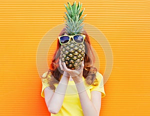 Fashion portrait woman and pineapple with sunglasses over colorful orange