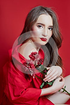 Fashion portrait of woman in red dress, beautiful makeup, curly long hair. Girl perfect lip makeup on red background