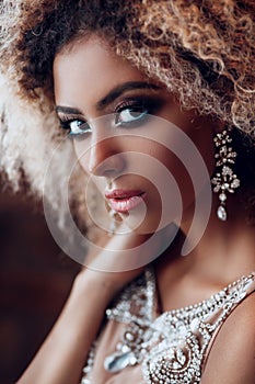 Fashion portrait of young beautiful afro american woman with jewelry and evening make-up.