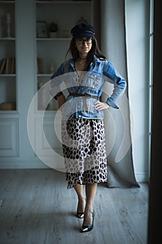 Fashion portrait of young beautiful female model standing in leopard dress in interior studio