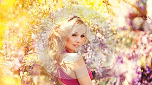 Fashion portrait of young beautiful girl posing against lilac bushes in blossom