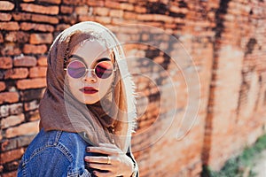 Fashion portrait of young beautiful muslim woman and old brick wall