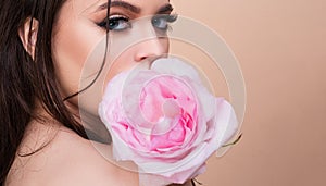 Fashion portrait of young beautiful woman with blue eyes and pink rose. Close-up portrait of a beautiful young girl with