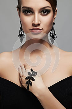 Fashion portrait of young beautiful woman in jewelry. elegant lady in black dress