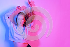 Fashion portrait of young elegant girl. Colored neon background, studio shot. Beautiful brunette woman. Hipster girl dancing in