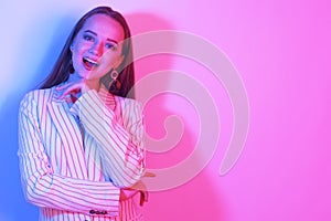 Fashion portrait of young elegant girl in a jacket. Colored neon background, studio shot. Beautiful brunette woman. Hipster girl