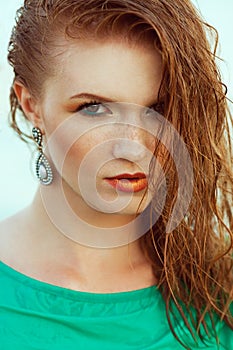 Fashion portrait of young model with wet long ginger red hair in azure summer dress. Perfect skin with freckles and stylish make