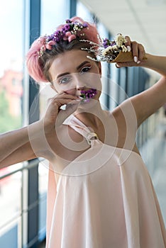 Fashion portrait of young woman with flowers her mouth