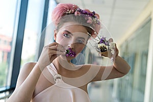 Fashion portrait of young woman with flowers in her mouth