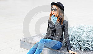 Fashion portrait young woman model wearing a black rock jacket hat in city