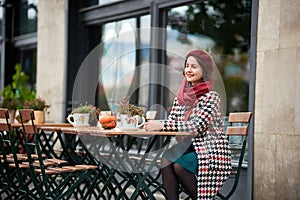 Fashion portrait of woman sitting in street cafe of Budapest