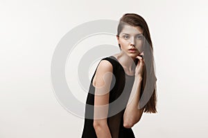 Fashion portrait of a young woman wth natural makeup and long hair looking at camera, over white background.