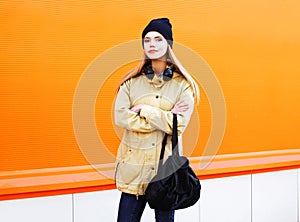 Fashion pretty blonde woman in city over a colorful orange