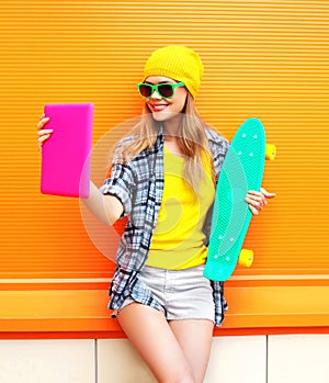 Fashion pretty cool girl makes self portrait on tablet pc over colorful orange