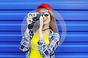 Fashion pretty cool girl wearing a colorful clothes with retro camera shooting