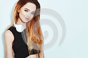 Fashion pretty cool woman in hat and headphones listening to music over pink background. Beautiful young teenage girl in hat