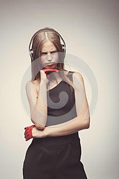 Fashion pretty girl listening music with headphones, wearing red gloves, and disappointed with bad music. Lifestyle woman concept