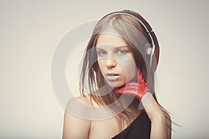 Fashion pretty girl listening music with headphones, wearing red gloves, take pleasure with song. Lifestyle woman concept