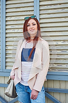 Fashion pretty redhead woman wearing in a pink jacket and stylish jeans