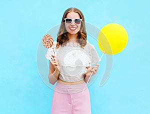 Fashion pretty smiling woman with air balloon and lollipop over colorful blue