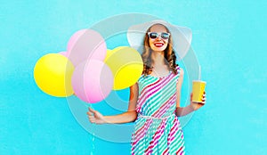 Fashion pretty smiling woman holds a fruit juice cup with an air colorful balloons