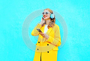 Fashion pretty smiling woman with smartphone listens to music in headphones