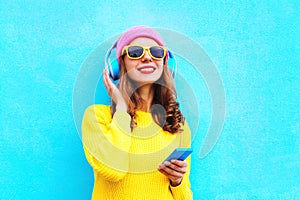 Fashion pretty sweet carefree girl listening to music in headphones with smartphone wearing colorful pink hat yellow sunglasses