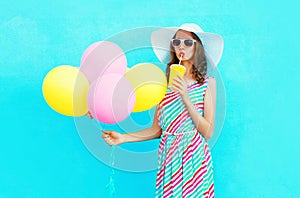 Fashion pretty woman drinks fruit juice from cup holds an air colorful balloons