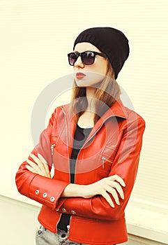 Fashion pretty woman with red lipstick wearing a rock leather jacket, sunglasses and black hat