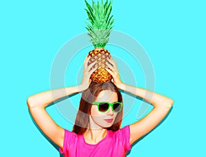 Fashion pretty woman in sunglasses with pineapple over blue