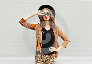 Fashion pretty woman wearing a black hat, sunglasses and jacket having fun over urban background