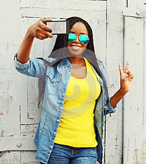 Fashion pretty young african woman taking self-portrait photo on a smartphone