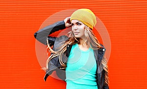 Fashion pretty young blonde woman wearing jacket hat looking in profile over colorful red