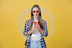 Fashion pretty young woman with fresh fruit juice cup in casual cloth having fun over colorful yellow background