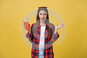 Fashion pretty young woman with fresh fruit juice cup in casual cloth having fun over colorful yellow background