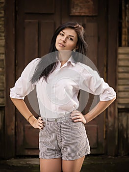 Fashion pretty young woman posing outdoor near a old wooden wall