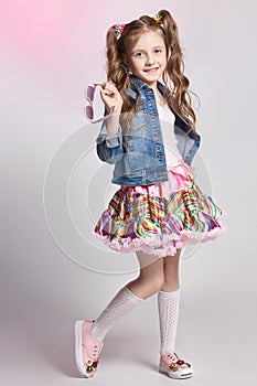 Fashion redhead girl in a festive outfit posing and smiling. Studio photo on light coloured background. Birthday, holiday