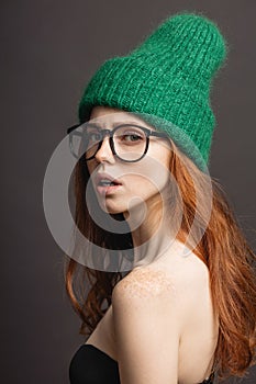 Fashion redhead Girl in Knitted Hat and galsses on grey background