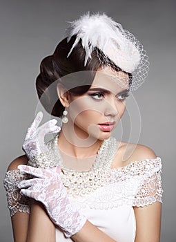 Fashion Retro elegant woman portrait. Wedding hairstyle. Brunette bride model present white hat, gloves and pearls jewelry access