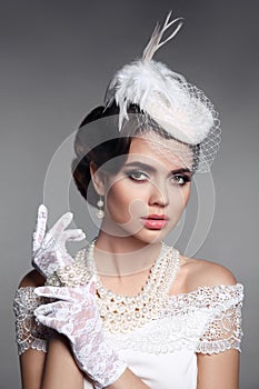 Fashion Retro elegant woman portrait. Wedding hairstyle. Brunette bride model present white hat, gloves and pearls jewelry access