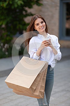 Fashion sale. Smiling girl with purchases outdoors. Recycled branding bag mockup