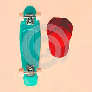 Fashion set. Skateboard and baseball cap on beige background, top view. Vintage hipster colorful photo